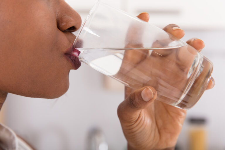 person drinking a glass of water